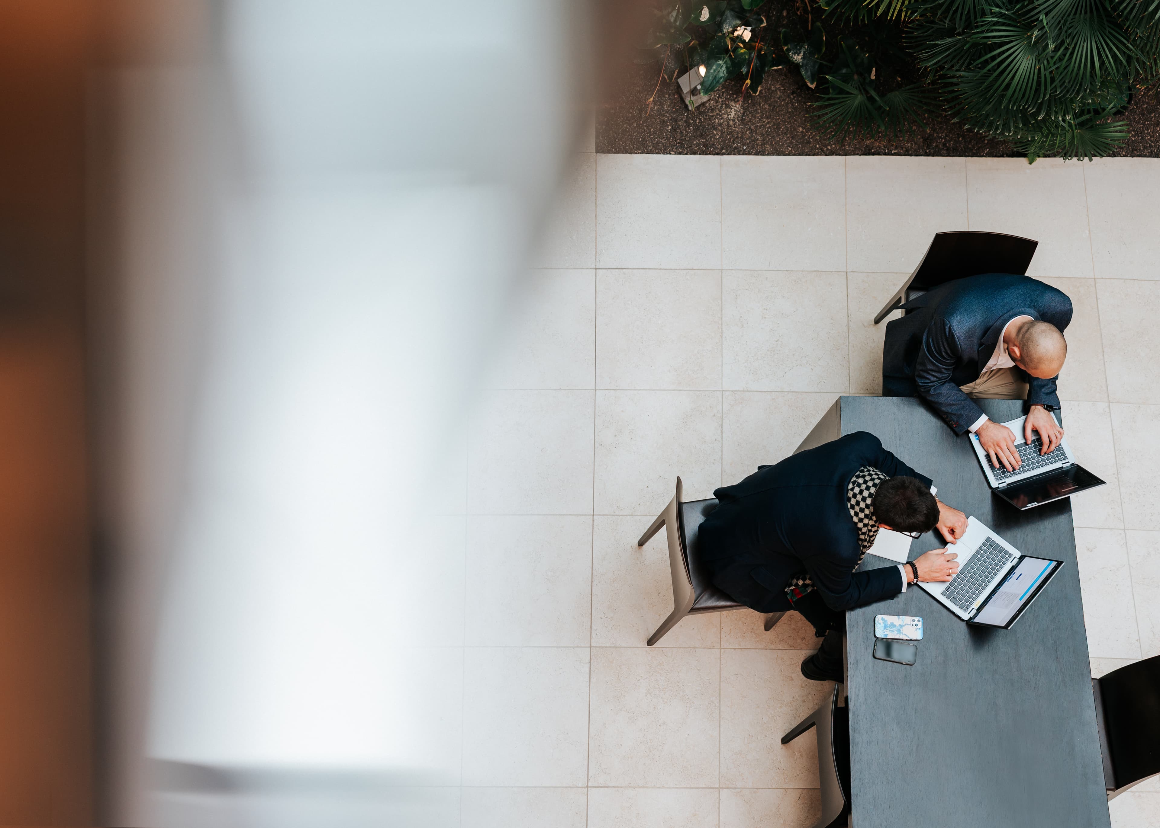 Zwei Baaderbank Mitarbeiter arbeiten im Banking Bereich an Laptops in moderner Büroumgebung.